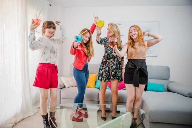 Vrouwen dansen met cocktails op de sofa