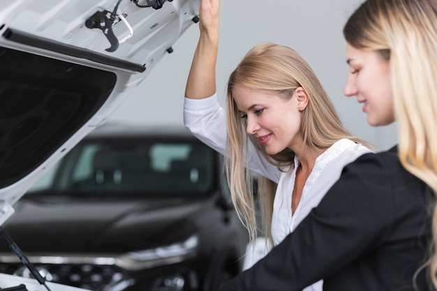 Gratis foto vrouwen die de auto in de showroom controleren