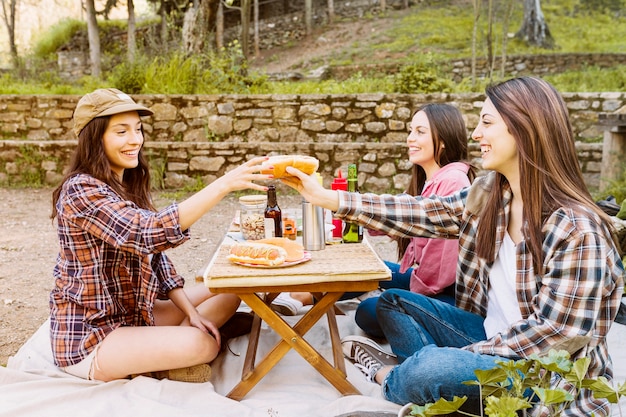 Vrouwen die hotdogs in de natuur eten