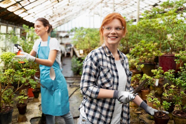 Vrouwen die in een kas voor hun planten zorgen