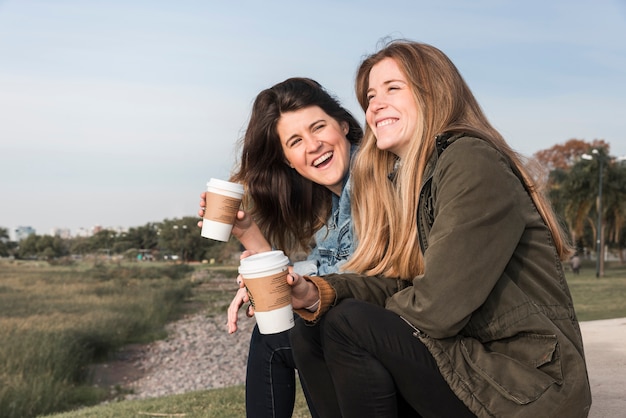 Vrouwen die koffie op aardachtergrond drinken