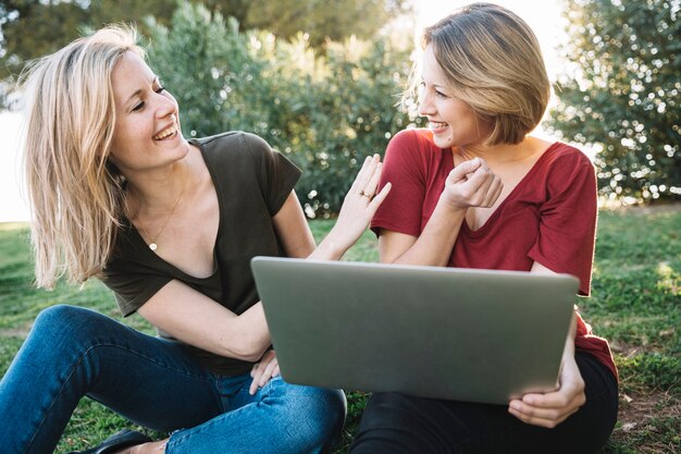 Vrouwen die laptop doorbladeren en lachen