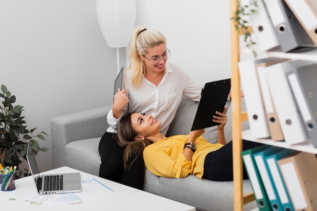 Gratis foto vrouwen die op een bank zitten en op een klembord kijken