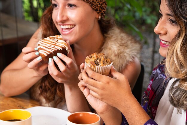 Vrouwen die snoepjes eten bij koffiewinkel