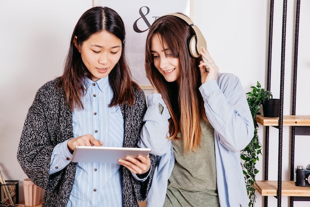 Gratis foto vrouwen die tablet gebruiken en naar muziek luisteren