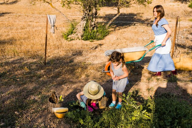 Vrouwen duwende kruiwagen met haar dochter het oogsten op het gebied
