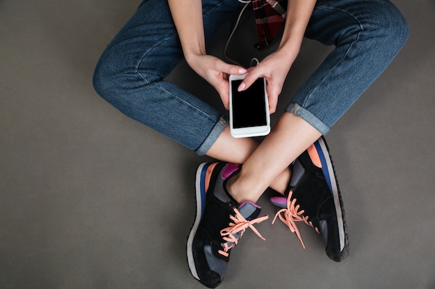 Vrouwen gekruiste benen en handen met leeg scherm mobiele telefoon