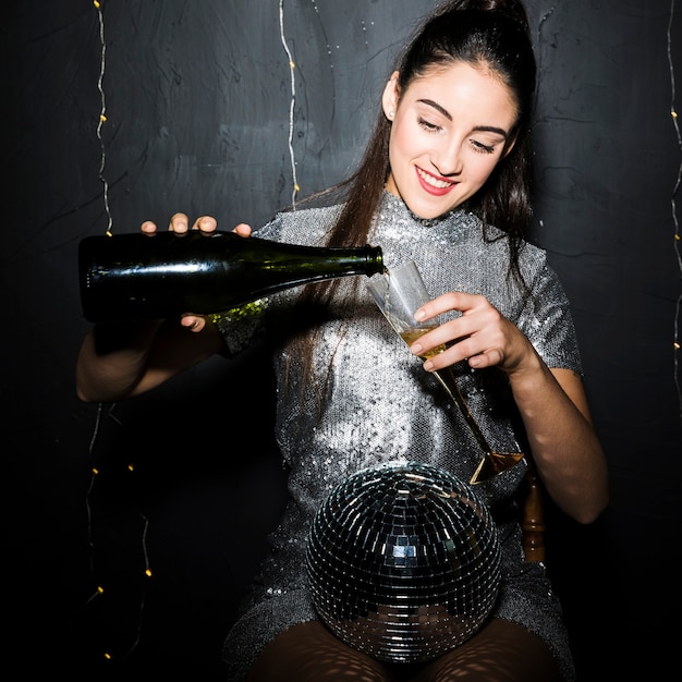 Vrouwen gietende champagne in glas dichtbij discobal
