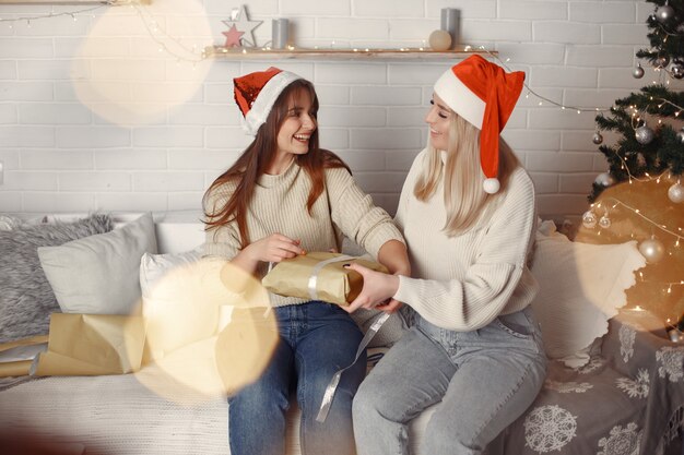 Vrouwen in een kamer. Blond in een witte trui. Dames in de buurt van kerstboom.