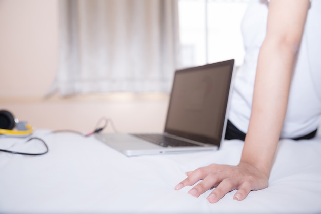 Vrouwen in een sportieve pyjama zitten of chatten online met vrienden of online winkelen. En ontspan in bed op vakantie.