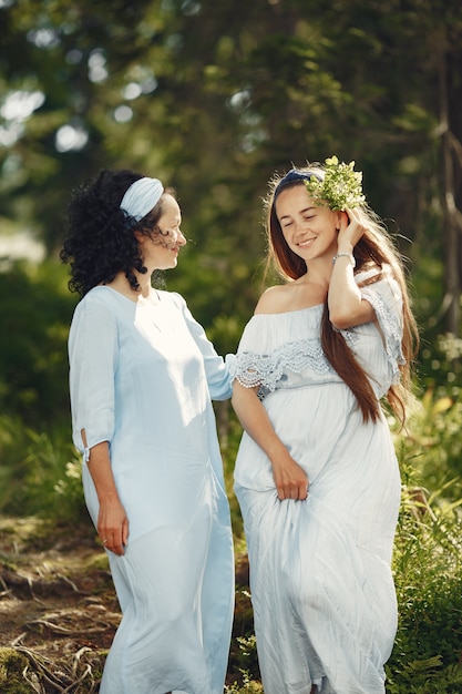 Vrouwen in een zomerbos. Dame in een blauwe jurk. Familie poseren en omarmen.