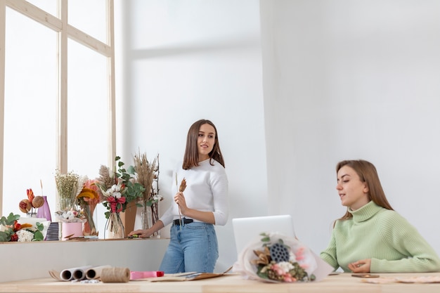 Gratis foto vrouwen in hun bloemenwinkel kijken ver