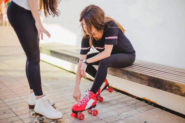 Vrouwen in leggings en shirt aan het aanraken van rollerskates