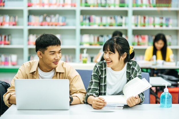 Vrouwen lezen boeken en mannen gebruiken laptops om in bibliotheken naar boeken te zoeken.