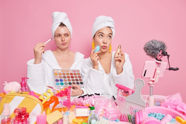 Gratis foto vrouwen maken gebruik van make-up cosmetische producten recensie maken instructievideo opnemen hoe je om jezelf kunt geven draag witte zachte badjassen poseren voor de smartphone