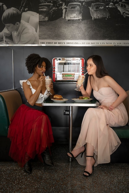 Vrouwen met hamburgers en drankjes aan tafel zitten