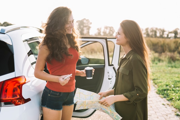 Vrouwen met kaart dichtbij auto
