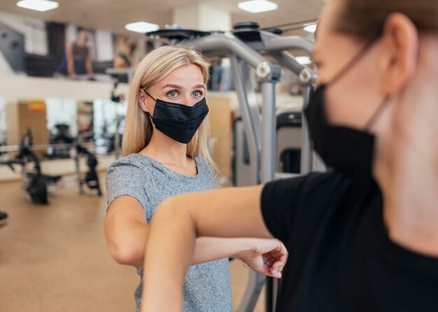 Vrouwen met medische maskers oefenen de ellebooggroet in de sportschool