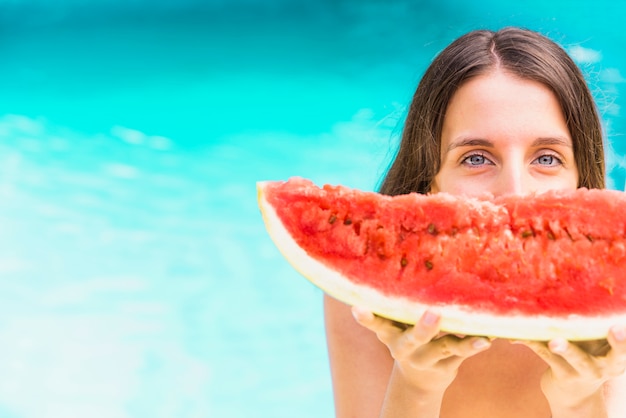 Vrouwen met watermeloen die zich dichtbij zwembad bevinden