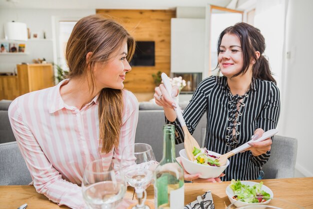 Vrouwen nemen salade met houten lepels
