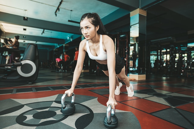 Vrouwen oefenen door de vloer te duwen met de Kettlebell in de sportschool.