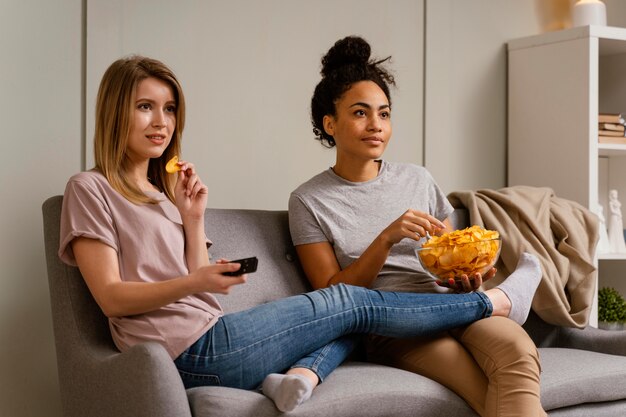 Vrouwen op de bank tv kijken en chips eten