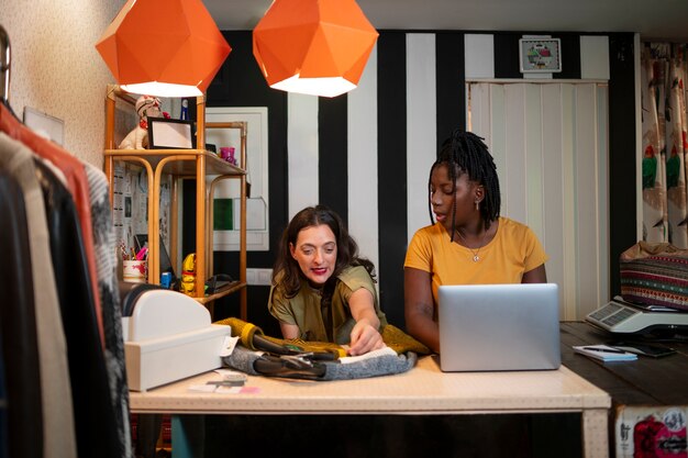 Gratis foto vrouwen organiseren kleding in de kringloopwinkel