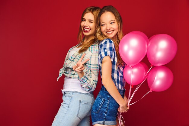 Vrouwen poseren met grote geschenkdoos en roze ballonnen