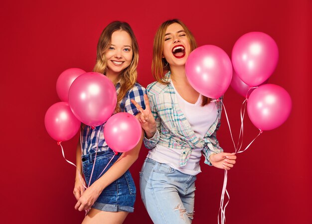 Vrouwen poseren met grote geschenkdoos en roze ballonnen