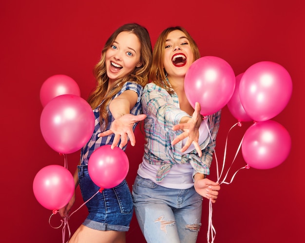 Vrouwen poseren met grote geschenkdoos en roze ballonnen