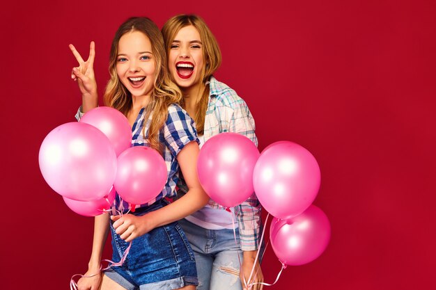 Vrouwen poseren met grote geschenkdoos en roze ballonnen