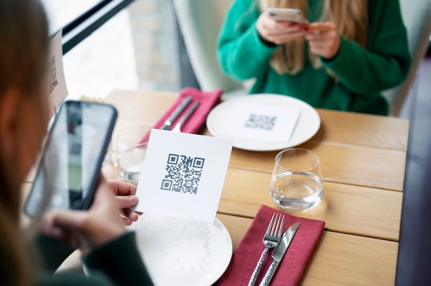 Gratis foto vrouwen scannen qr-code in restaurant