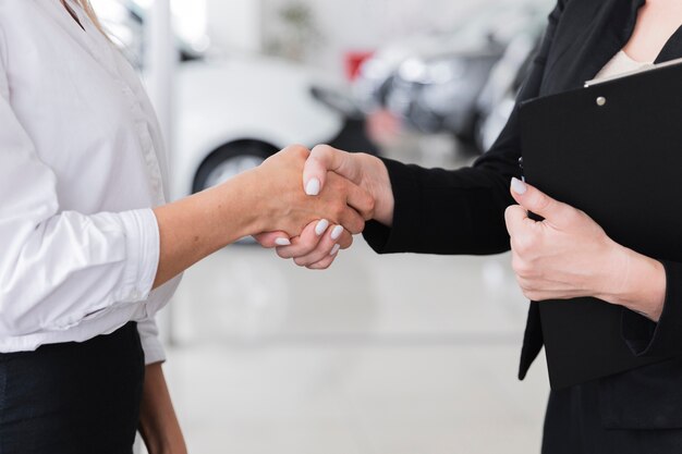 Gratis foto vrouwen schudden handen in auto showroom