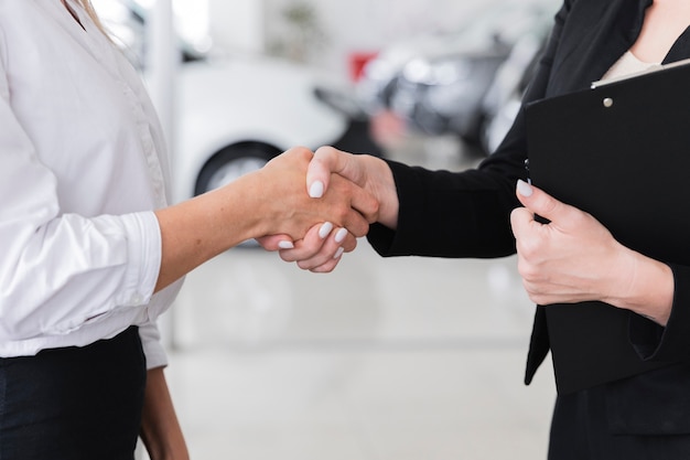 Vrouwen schudden handen in auto showroom