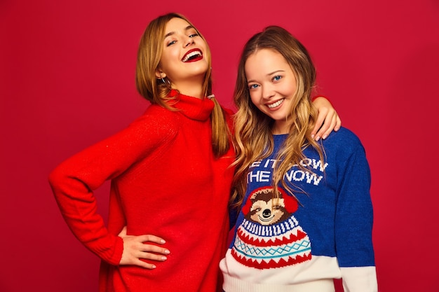 Vrouwen staan in stijlvolle winter warme truien op rode muur