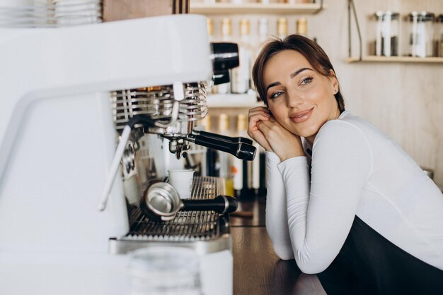 Vrouwenbarista bij een koffiewinkel die koffie bereidt