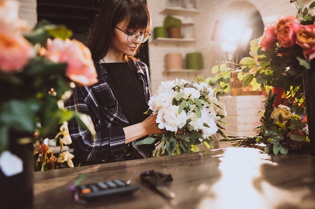 Vrouwenbloemist bij haar eigen bloemenwinkel die bloemen behandelen