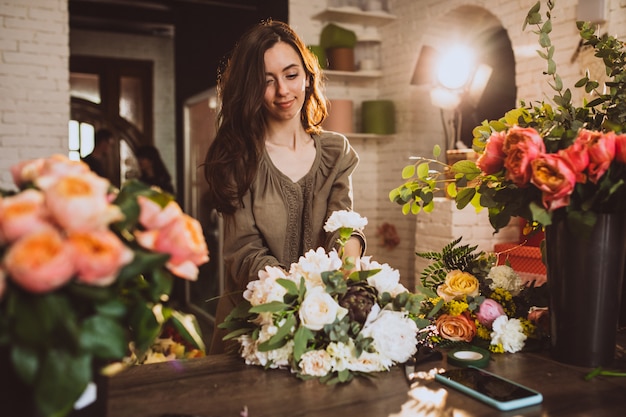 Vrouwenbloemist bij haar eigen bloemenwinkel die bloemen behandelen