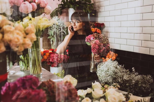 Vrouwenbloemist bij haar eigen bloemenwinkel die bloemen behandelen