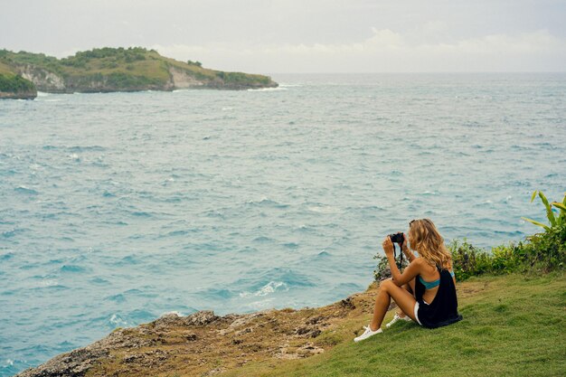 Vrouwenfotograafreiziger die oriëntatiepunten op camera fotograferen, Angel's Billabong-strand, Nusa Penida-eiland, Bali, Indonesië.