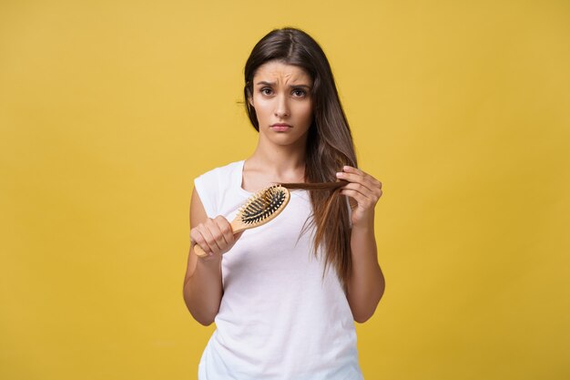 Vrouwenhand die haar lange haar vasthoudt en kijkt naar beschadigde gespleten punten van haarverzorgingsproblemen.