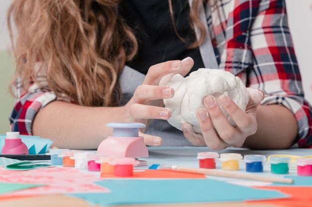 Vrouwenhand die witte klei voor ambacht kneden