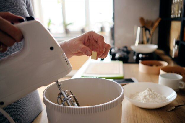 Vrouwenhanden die een witte handbediende mixer gebruiken