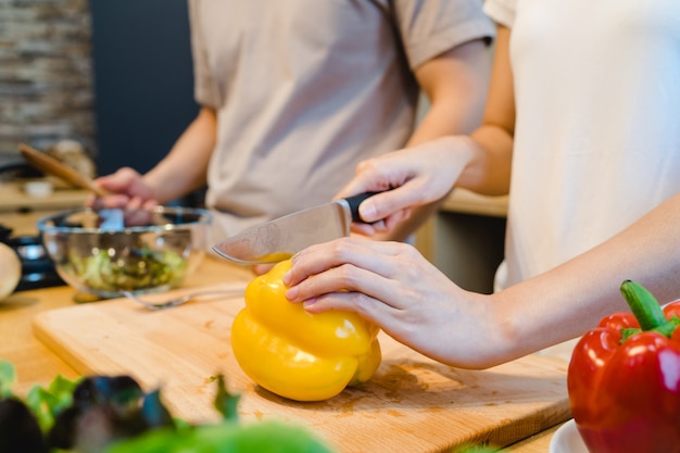 Vrouwenhanden die groene paprika in de keuken snijden