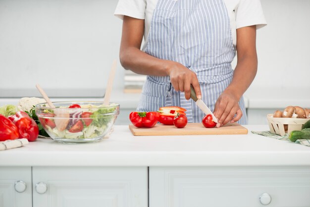 Vrouwenhanden die verse tomaten voor salade snijden