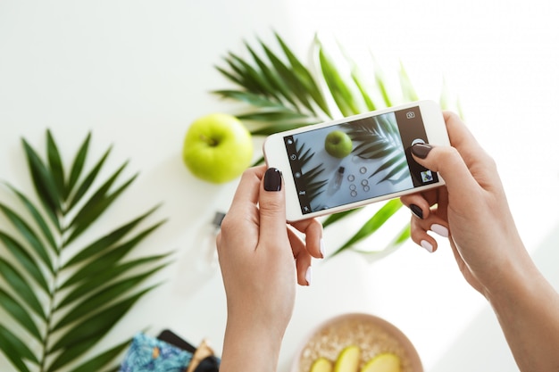 Vrouwenhanden met de modieuze telefoon die van de nagellakholding beelden nemen.