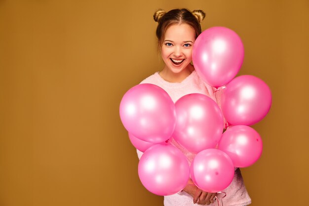 Vrouwenmodel met roze luchtballons op gouden muur