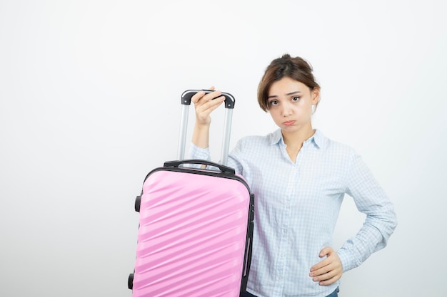 Vrouwentoerist die roze reiskoffer staat en houdt. Hoge kwaliteit foto