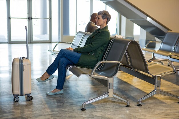 Vrouwenzitting met bagage bij wachtruimte