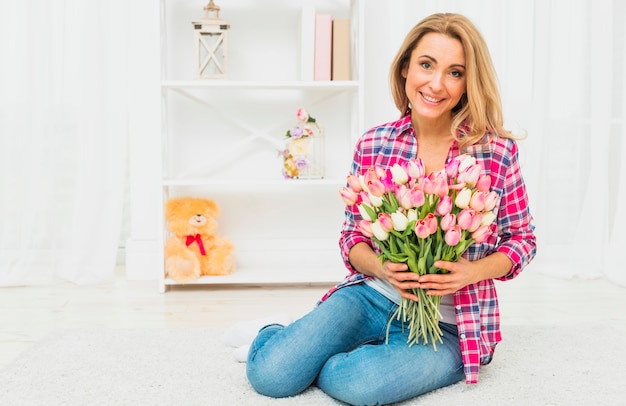 Vrouwenzitting met tulpenbloemen op vloer